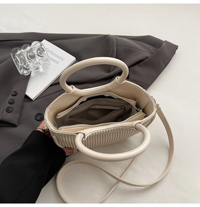 Detail view of cream pleated bag interior showing grey lining and zippered pocket