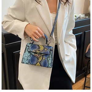 Detail of colorful snakeskin pattern handbag with metal turn-lock on white blazer