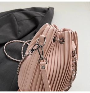 Detailed view of pink pleated bucket bag with metallic gunmetal chain strap