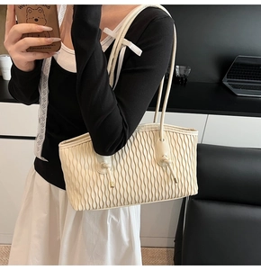 Detailansicht der cremeweißen Falten-Tote-Bag mit feiner Textur und Dekoknoten