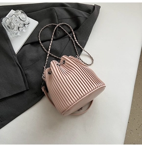 Detail of pink pleated bucket bag with metal chain strap and drawstring closure
