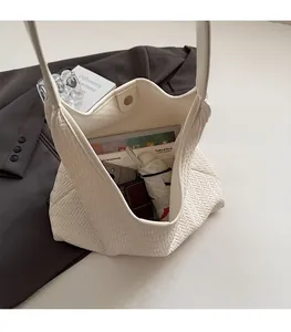 White woven Hobo bag with spacious interior holding a wallet, umbrella, and tablet