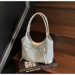 Close-up of light blue denim tote with silver rhinestone bow on dark wood steps