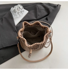Detail view of beige drawstring bucket bag interior showing pockets and drawstring closure