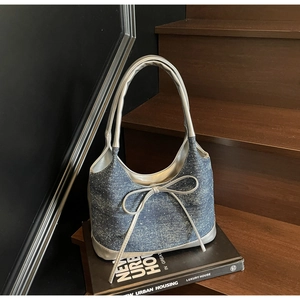 Detail of blue denim tote bag with glitter finish, large bow, and silver metallic trim