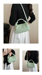 Detail of mint green pleated handbag showing knotted handle and vegan leather texture