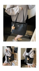 Detail of black woven tote bag with cute bear charm and elegant metallic brand plate
