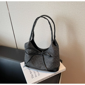 Detail view of denim shoulder bag with polka dots and large black bow decoration
