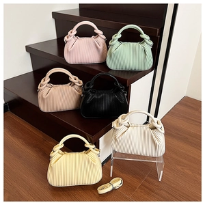Pleated handbags in multiple colors displayed on wooden stairs with knotted handles