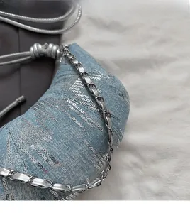 Détail du sac en denim bleu clair avec paillettes argentées et bandoulière en chaîne
