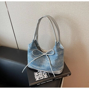Detail of blue denim shoulder bag with silver leather trim and shiny bow decoration