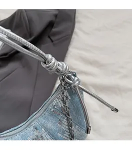 Détails d'un sac en jean bleu pailleté avec bandoulière en cuir argenté noué et chaîne