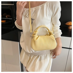 Detail of yellow pleated cloud bag featuring textured fabric and leather crossbody strap