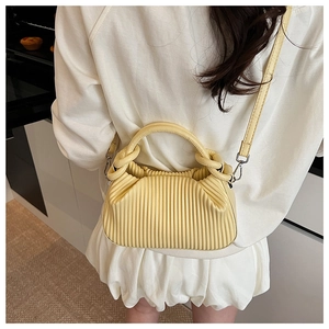 Detail of light yellow ruched bag with vertical textures and adjustable shoulder strap