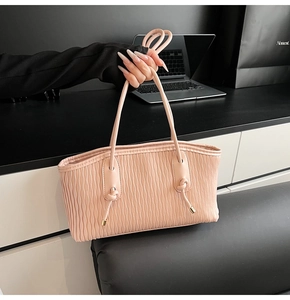 Details einer rosa Plissee-Einkaufstasche mit schmalen Griffen und Metallbeschlag