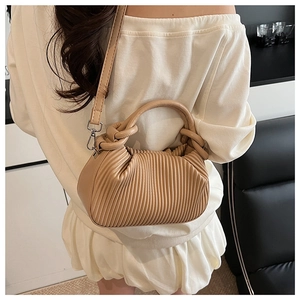 Detail of beige pleated handbag with soft twisted handle and adjustable strap