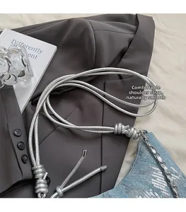 Détail du sac dumpling en jean bleu avec paillettes argentées et bandoulière à nœuds