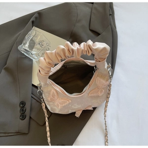 Detail of pink embroidered butterfly bag showing inner zipper compartment and chain