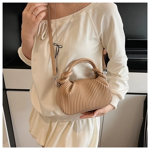 Detail view of beige pleated crossbody bag with dual handles and silver-tone hardware