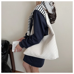 Macro detail of the white woven texture and shoulder strap on a large tote bag