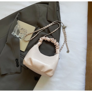 Detail of light pink dumpling bag featuring pleated cloud handle and silver chain strap
