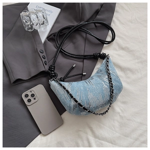 Détail du sac croissant en denim bleu clair avec paillettes argentées et chaîne