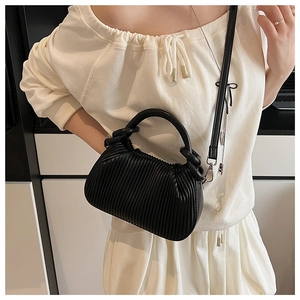 Detail of black pleated texture handbag featuring curved handles and detachable strap