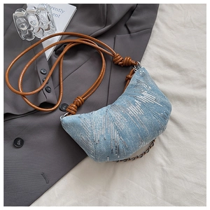 Détail du sac croissant en denim bleu avec paillettes argentées et bandoulière marron