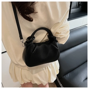 Detailed view of black pleated handbag with silver hardware and detachable strap