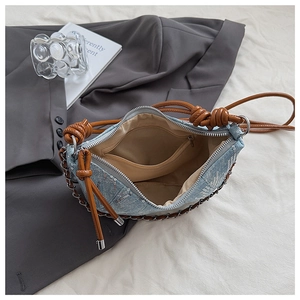 Détail du sac dumpling en jean bleu avec paillettes, sangle tressée et poche intérieure zippée