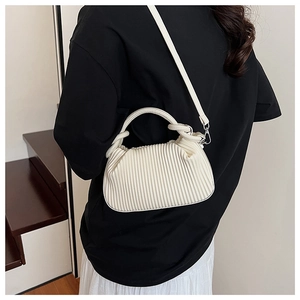 Detailed view of cream white pleated shoulder bag worn by model in a minimalist setting