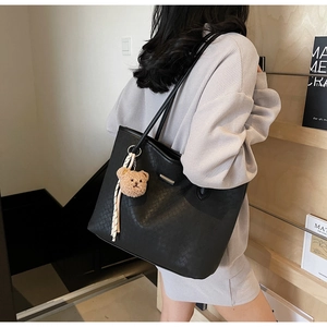 Detail of black woven tote bag with cute plush bear pendant for daily commute style