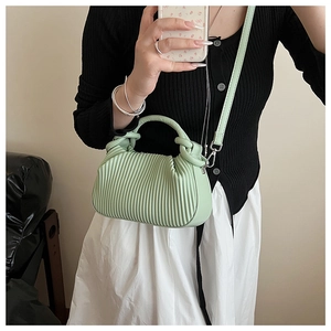 Mirror selfie showing mint green pleated handbag with knotted handle and long strap