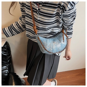 Détail du sac croissant en denim à paillettes bleu clair avec chaîne et bandoulière nouée