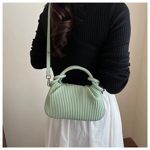 Detailed view of a mint green pleated cloud bag styled with a summer commute outfit