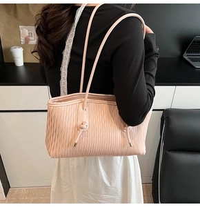 Detail der rosa Plissee-Tasche mit goldenen Kordelenden und eleganter Wellenstruktur