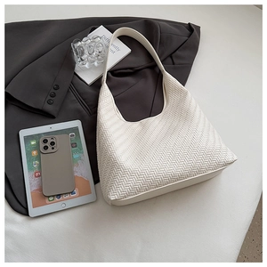 Detailed view of cream woven shoulder bag with vegan leather texture on a blazer