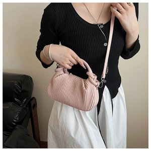 Detail of pink ruched handbag with decorative knot handle and crossbody strap