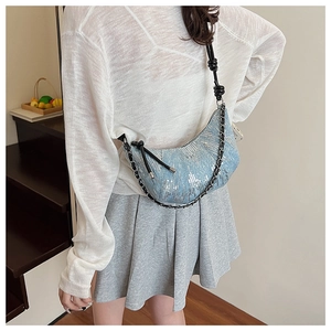 Détail du sac croissant en denim bleu clair avec paillettes argentées et sangle à nœuds