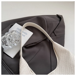Close-up of cream woven leather texture and hobo shoulder strap of a minimalist bag