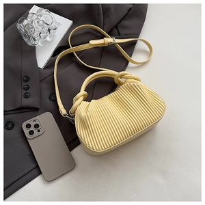Top view of yellow pleated handbag with round handle on a chic grey background