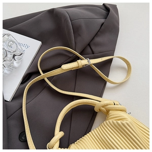 Detailed view of pale yellow pleated handbag with braided knot handle on grey blazer