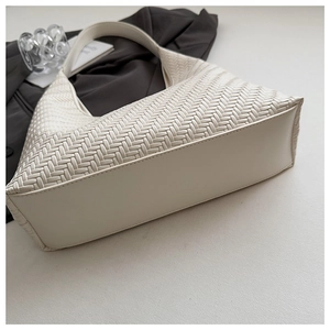 Detail view of woven leather texture on a cream hobo shoulder bag with a curved base