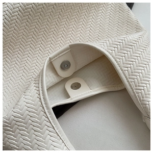 Close-up of beige woven leather texture and silver magnetic metal clasp detail