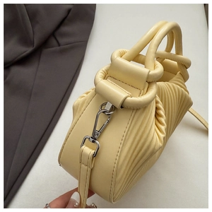 Detail of light yellow ruched bag showing 3D pleated texture and silver metal hardware