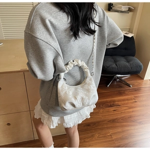 Detail of white butterfly embroidery and ruffled handle on a vintage style crossbody bag