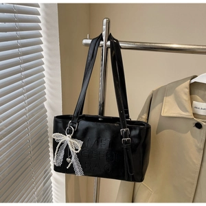 Detail der glänzenden schwarzen PU-Lederhandtasche mit Perlenspitzenbogen und Metallschnalle