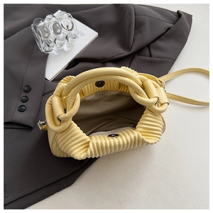 Macro view of pale yellow pleated bag showing herringbone lining and magnetic closure
