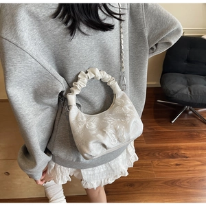 Close-up of white butterfly embroidery and ruffled cloud handle on a small handbag
