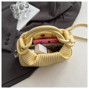 Top-down view showing yellow ruched cloud bag interior with smartphone and makeup essentials